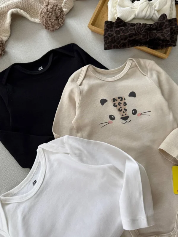 نمای نزدیک بادی نوزادی H&M طرح هاپو و پلنگی به همراه بادی‌های ساده مشکی و سفید