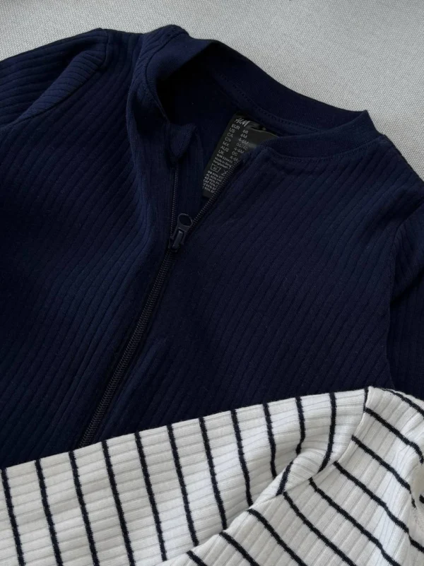 نمای نزدیک از پارچه کبریتی و زیپ سرهمی نوزادی سرمه‌ای رنگ H&M
