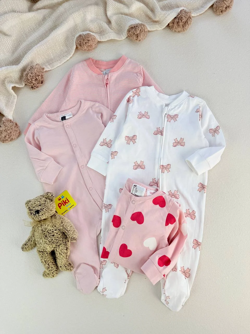 کالکشن سرهمی نوزادی دخترانه H&M؛ انتخابی رویایی برای سیسمونی مجموعه چهار عددی سرهمی نوزادی دخترانه اچ اند ام با طرحهای راهراه، قلب و پاپیون در رنگهای صورتی و سفید همراه با عروسک خرس