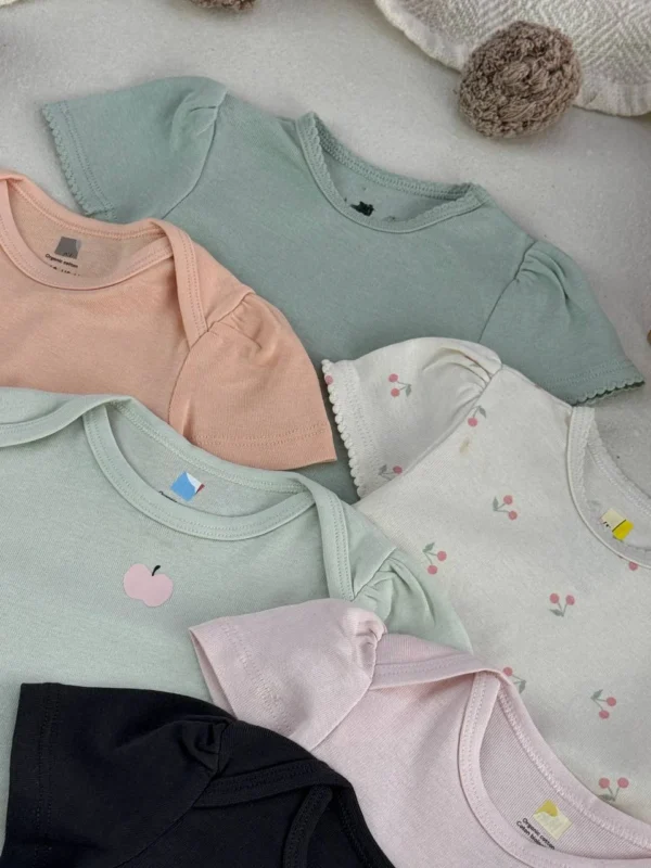 نمای نزدیک بادی نوزادی دخترانه H&M با سرشانه چیندار در رنگ‌های پاستلی سبز سدری، هلویی و صورتی با طرح گیلاس