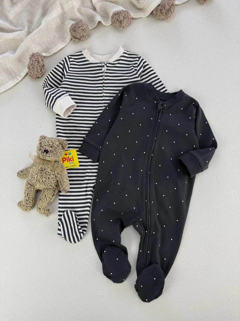 ست دو تایی سرهمی جورابدار نوزادی طرح خالخالی و راهراه؛ برند H&M ست دو تایی سرهمی جورابدار نوزادی مشکی خالخالی و راهراه مشکی سفید با زیپ در کنار عروسک خرس