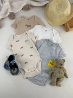 ست کامل بادی آستین کوتاه نوزادی H&M در رنگ‌های خنثی با طرح سگ داشوند همراه با کلاه حصیری، عروسک خرس و کفش نوزادی