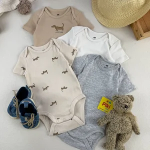 ست کامل بادی آستین کوتاه نوزادی H&M در رنگ‌های خنثی با طرح سگ داشوند همراه با کلاه حصیری، عروسک خرس و کفش نوزادی